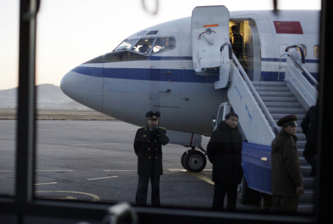 In this file photo taken Monday, Dec. 19, 2011, North Korean officials wait for passengers to board an Air China flight at Pyongyang airport in Pyongyang, North Korea. State-owned airline Air China suspended flights Tuesday between Beijing and North Korea due to a lack of demand, deepening the North's isolation amid mounting UN sanctions over its nuclear and missile programs. (AP-Yonhap)