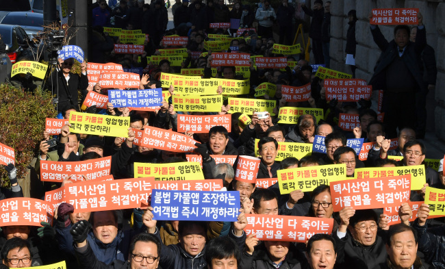 Members of Seoul’s representative taxi unions stage a protest over the legality of 24-hour carpooling services in front of Seoul’s City Hall on Tuesday. (Yonhap)