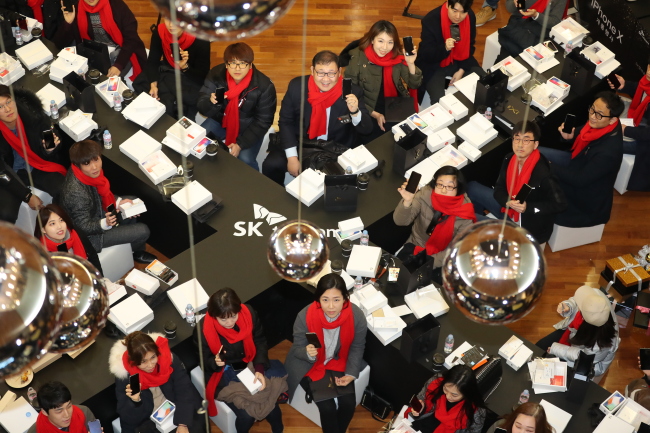 IPHONE X IN SEOUL -- Customers hold up the iPhone X at an SK Telecom store in Seoul, Friday. The iPhone X, which Apple designed as its 10th anniversary smartphone, officially became available for purchase through Korea’s three mobile carriers SK Telecom, KT and LG Uplus on the day. (Yonhap)