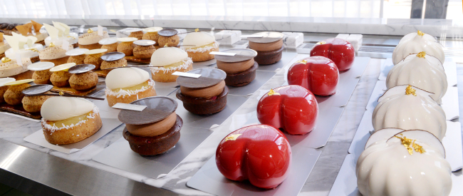 Patisserie by Garuharu has a line-up of toothsome sweets including their Coco (far right) -- which combines a vanilla-white chocolate mousse with passion fruit cream and coconut streusel -- Amour (second from right) -- a pistachio mousse with cherries -- and their Couvee Bali Brownie (third from right). (Photo credit: Park Hyun-koo/The Korea Herald)