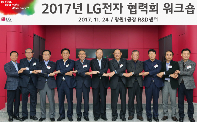 LG Elec. Vice Chairman & CEO Jo Seong-jin (sixth from left) holds hands with the heads of its contractors at LG Electronics' R&D Center in Changwon, South Gyeongsang Province, on Friday. (LG Electronics)