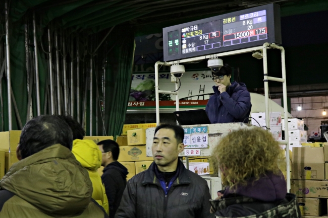 An auctioneer stands at a podium in front of bidders at Garak Wholesale Market in Seoul. (Son Ji-hyoung/The Korea Herald)