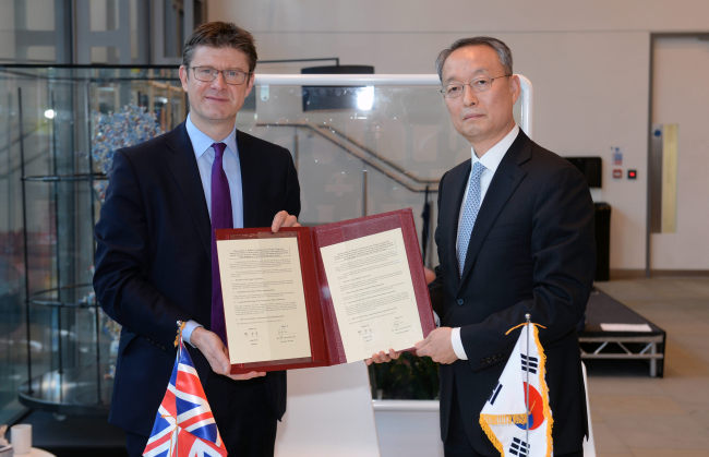 Trade Minister Paik Un-gyu and his British counterpart Greg Clark sign a memorandum of understanding in London on Monday. (Yonhap)