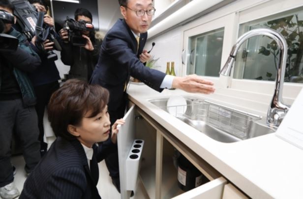 In this photo taken Nov. 29, 2017, and provided by the transport ministry, Land, Infrastructure and Transport Minister Kim Hyun-mee sits down to look at the kitchen sink of a public rental home in southern Seoul. (Yonhap)