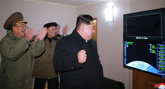 북한이 29일자 노동당 기관지 노동신문을 통해 공개한 신형 대륙간탄도미사일(ICBM) ‘화성-15형’ 시험발사 모습.미사일이 북한이 새로 개발한 ‘9축 자행발사대차’(바퀴 축이 9개인 새로운 이동식 발사차량)에 탑재된 뒤 수직으로 세워진 후 발사되는 장면과 김정은 노동당 위원장이 발사 관계자들과 함께 기뻐하고 있는 모습이 담겼다. [제공=노동신문·연합뉴스]