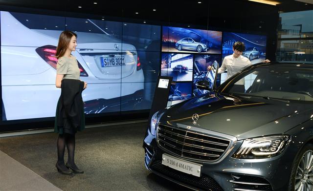 모델들이 LCD 사이니지(모델명: 55VH7B) 18대를 이어 붙인 대형 비디오월 앞에서 차량을 살펴보고 있다.