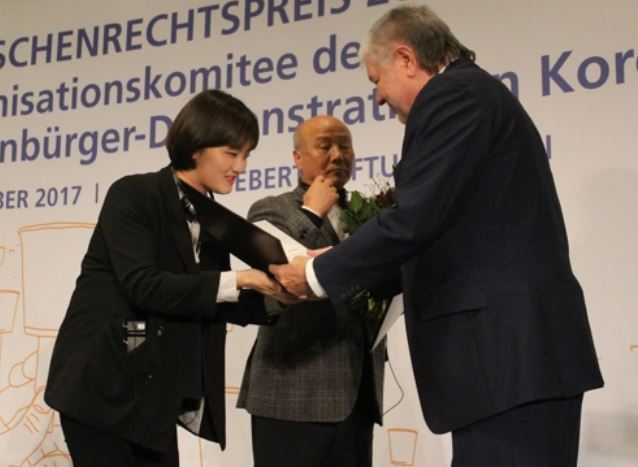 Jang Ae-jin (L), a survivor of the 2014 Sewol ferry sinking, receives the 2017 FES Human Rights Award from Kurt Beck, head of the German political foundation Friedrich-Ebert-Stiftung (FES), during a ceremony in Berlin on Dec. 5, 2017. Jang received the award on behalf of South Koreans who took part in candlelight rallies last year to call for then-President Park Geun-hye's resignation over an influence-peddling scandal. (Yonhap)