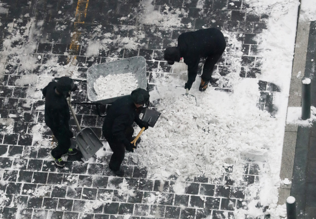 Public workers remove snow from the streets on Sunday morning. (Yonhap)
