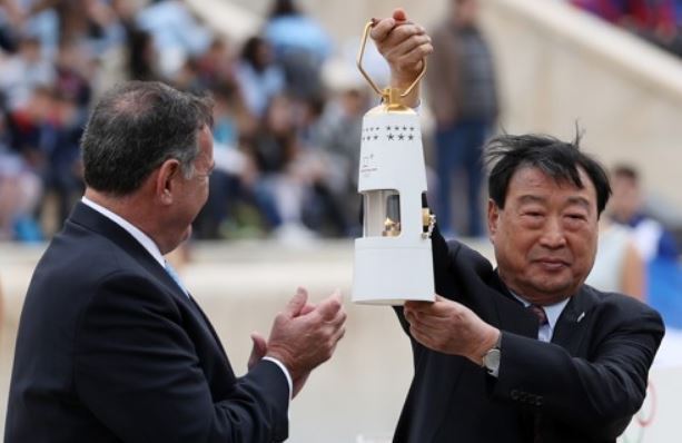 In this file photo taken Oct. 31, 2017, Lee Hee-beom (R), head of the 2018 PyeongChang Winter Olympics organizing committee, holds up a lamp containing the Olympic flame during a ceremony at the Panathenaic Stadium in Athens. (Yonhap)