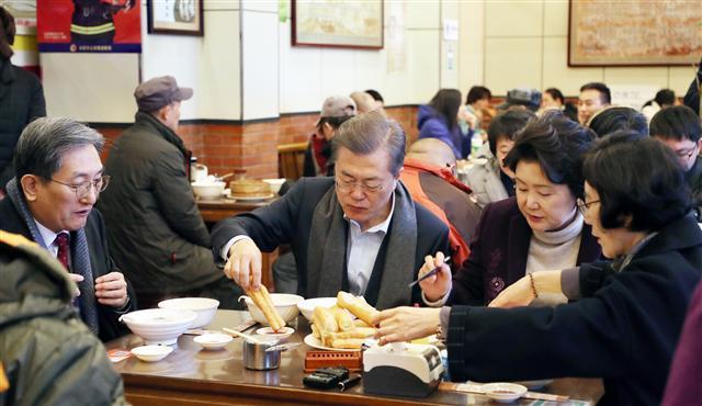 문재인 대통령과 부인 김정숙 여사가 14일 오전 중국 베이징 조어대 인근 한 현지 식당에서 중국인들이 즐겨 먹는 아침 메뉴 중 하나인 유탸오와 더우장으로 식사하고 있다. 유탸오는 밀가루를 막대 모양으로 빚어 기름에 튀긴 꽈배기 모양의 빵으로 겉은 바삭하고 속은 말랑한 식감이 특징이다. 중국식 두유인 더우장에 적셔서 먹는 중국 일반 시민의 대표적인 아침 식사다. 왼쪽은 노영민 주중 한국대사.  [청와대사진기자단=연합뉴스]