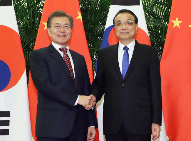 President Moon Jae-in and Chinese Prime Minister Li Keqiang shake hands ahead of their meeting in Beijing on Friday. Yonhap