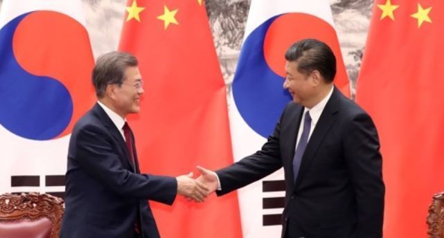 South Korean President Moon Jae-in (L) and Chinese President Xi Jinping shakes hands in an agreement-signing ceremony held shortly after their bilateral summit in Beijing on Dec. 14, 2017. (Yonhap)