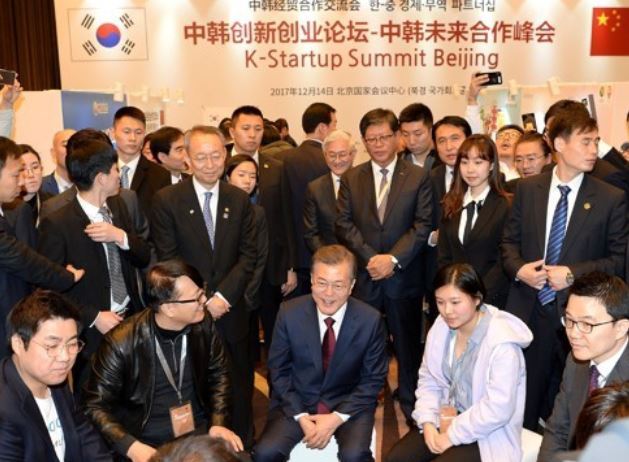 President Moon Jae-in (C) talks with Korean startup company officials while visiting a business forum hosted by the Korea Trade-Investment Promotion Agency (KOTRA) in Beijing on Dec. 14, 2017, in this photo provided by the agency. (Yonhap)