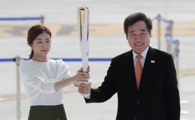 In this file photo taken on Nov. 1, 2017, former Olympic figure skating gold medalist Kim Yu-na (L) and South Korean Prime Minister Lee Nak-yon hold the torch for the 2018 PyeongChang Winter Olympics during the ceremony marking the arrival of the Olympic flame at Incheon International Airport. (Yonhap)