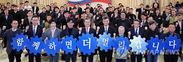 President Moon Jae-in (front row, fifth from L) poses for a group photo while holding up a sign that says "Together, we go further," in a meeting with a group of officials and workers from a joint public fund held at his office Cheong Wa Dae in Seoul on Dec. 21, 2017.