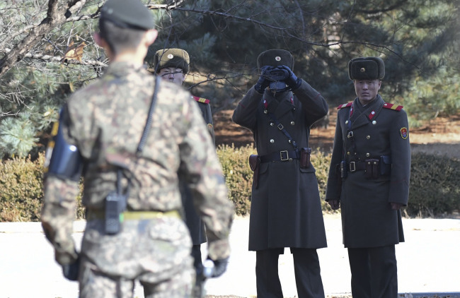 A South Korean soldier is seen standing guard as three North Korean soldiers observe the south side of Panmunjeom in a photograph taken on Nov. 27. Yonhap