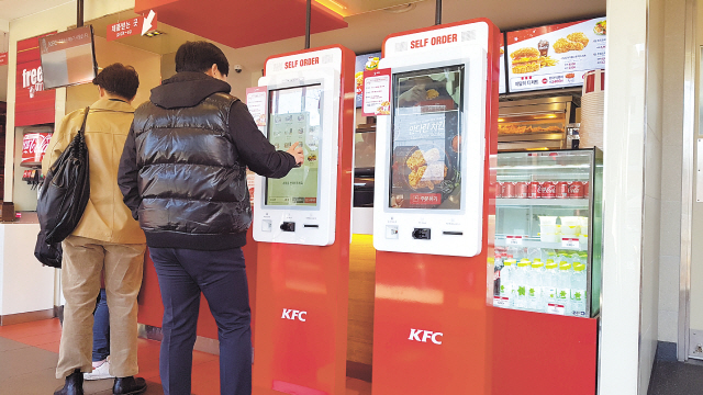 패스트푸드점에서 한 소비자가 키오스크를 이용해 메뉴를 주문하고 있다.