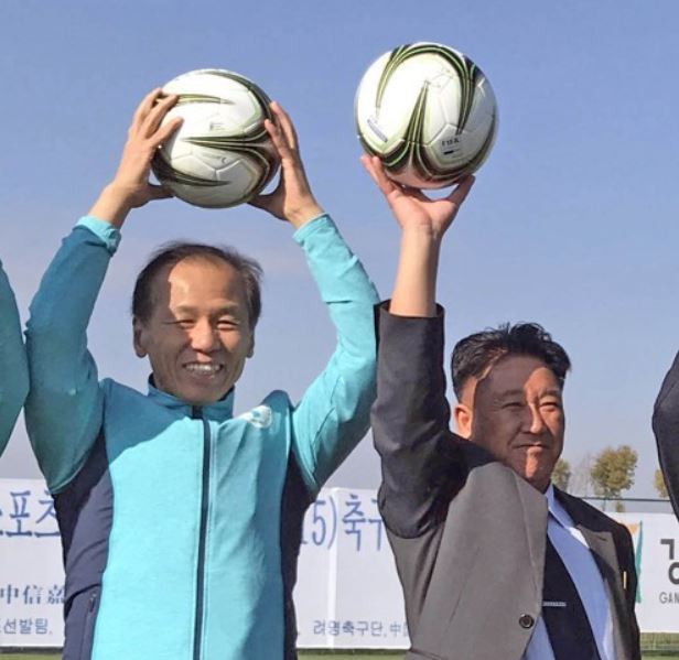 This file photo shows Gangwon Governor Choi Moon-soon (L) and Mun Ung, the chairman of the North's April 25 Athletic Committee, posing for a photo at an international youth football championship in the Chinese city of Kunming in late December of 2017. (Yonhap)
