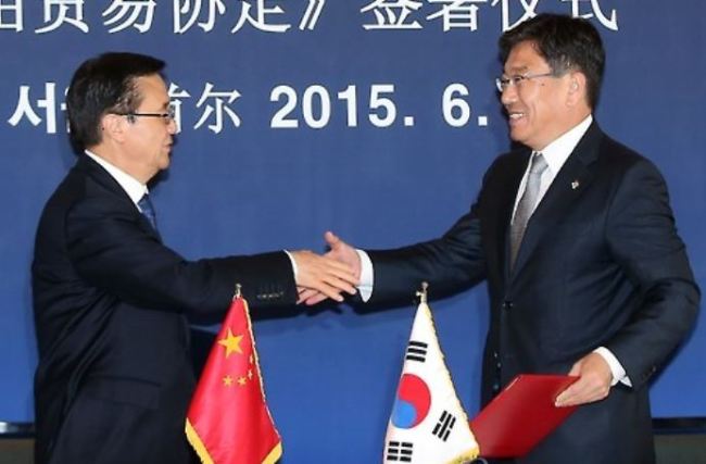South Korean Trade Minister Yoon Sang-jick (R) and his Chinese counterpart Gao Hucheng shake hands after officially signing a free trade agreement at a Seoul hotel on June 1, 2015. (Yonhap)