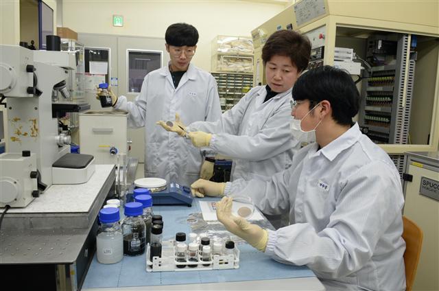 ETRI 연구진이 친환경 용매인 물과 나트륨 이온을 활용해 제조된 2차원 나노시트가 분산되어 있는 수용액을 살펴보고 있다. [제공=ETRI]