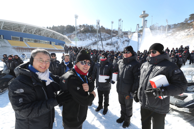 10일 오전 강원도 평창 스키점프센터 앞에서 KT 황창규(앞줄 왼쪽) 회장이 현장직원에게 혹한에도 따뜻하게 평창동계올림픽을 준비할 수 있도록 ‘발열조끼’를 입혀주고 있다.［제공=KT］