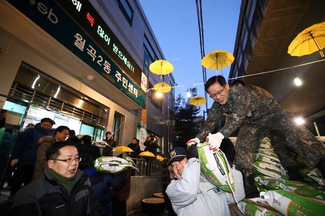 서울 성북구 월곡2동주민센터 직원들과 경찰 군인까지 나서 ‘얼굴없는 천사’가 새벽에 몰래 놓고 간 쌀을 옮기고 있다.  [제공=서울 성북구]