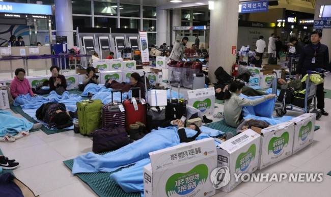 강풍과 폭설로 무더기로 결항한 제주공항 항공편 이용객들이 12일 새벽 제주도와 한국공항공사 제주지역본부가 제공한 매트리스와 담요를 활용해 새우잠을 자고 있다. (사진=연합뉴스)