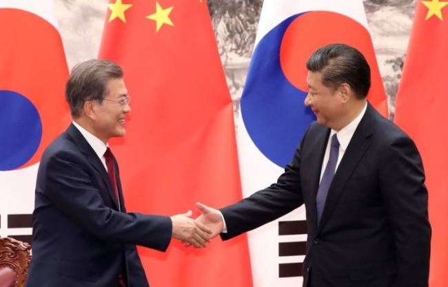 President Moon Jae-in, left, shakes hands with Chinese President Xi Jinping during Moon's visit to China in December last year. (Yonhap)