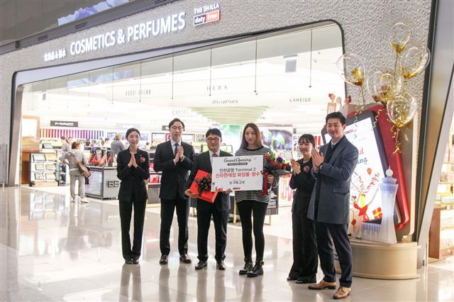 인천국제공항 제2터미널이 18일 개장하면서 신라면세점의 화장품ㆍ향수 매장 오픈과 동시에 첫 구매고객도 탄생했다. 신라면세점 인천공항점장 고선건 상무(왼쪽에서 세번째)가 첫 구매 고객에게 꽃다발과 함께 화장품과 향수로 구성된 선물을 증정하고 있다.   [제공=신라면세점]