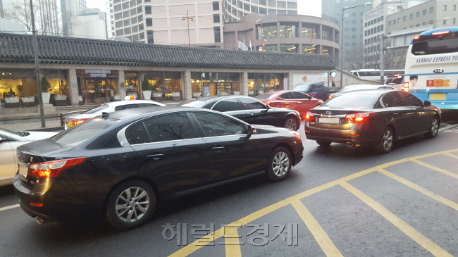 18일 오전 8시 서울 중구 정동 일대 도로가 출근길 승용차로 가득차 있는 모습(왼쪽 사진)과 시민들이 서울형 미세먼지 저감조치에 따른 차량 2부제 권장 캠페인을 벌이고 있는 모습.  이원율 기자/yul@heraldcorp.com