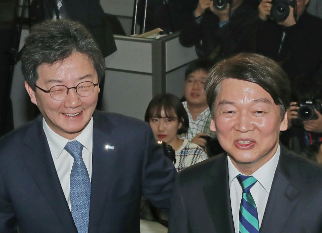 Ahn Cheol-soo, the leader of the People's Party, and Yoo Seong-min, the leader of the Bareun Party, hold a press conference to officially declare their merger at the National Assembly in Seoul on Jan. 18, 2018. (Yonhap)
