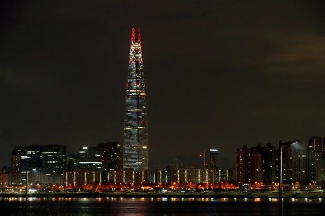 지난 14일 서울 동대문 인근에서 성화봉송 주자로 나선 그룹 2AM 출신 가수 정진운과 예술가의 꿈을 키우고 있는 ‘미래의 춤신춤왕’ 청소년들이 코카콜라 응원 스태프들의 응원을 받고 있다(왼쪽 사진). 롯데는 평창동계올림픽이 끝날 때까지 롯데월드타워에 LED 조명 2만6000개를 활용해 성화를 밝힌다.  [제공=코카콜라·롯데그룹]