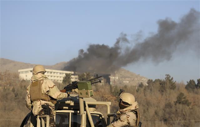 <YONHAP PHOTO-4298> Afghan security personnel stand guard as smoke rises from the Intercontinental Hotel after an attack in Kabul, Afghanistan, Sunday, Jan. 21, 2018. Gunmen stormed the hotel in the Afghan capital on Saturday evening, triggering a shootout with security forces, officials said. (AP Photo/Rahmat Gul)/2018-01-21 14:59:09/ <저작권자 ⓒ 1980-2018 ㈜연합뉴스. 무단 전재 재배포 금지.>