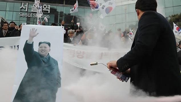 Police extinguish a picture of North Korean leader Kim Jong-un that was set on fire by conservative activist groups during an anti-North Korea rally in front of Seoul Station on Jan. 22, 2018. (Yonhap)