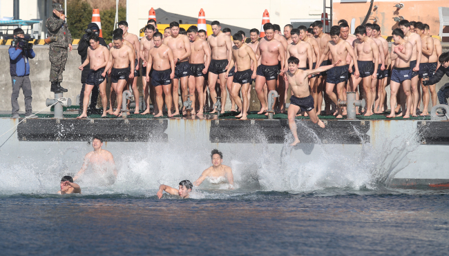 WINTER SEA TRAINING -- Members of the South Korean Navy’s Ship Salvage Unit jump into the sea near Jinhae Man in the country’s southern coast as part of its winter training. (Yonhap)