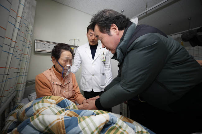 Prime Minister Lee Nak-yon holds the hands of an elderly woman injured in a hospital fire in South Korea's southeastern city of Miryang on Jan. 26. (Yonhap)