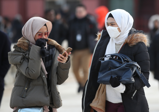 Tourists bundle up in central Seoul, Sunday. (Yonhap)
