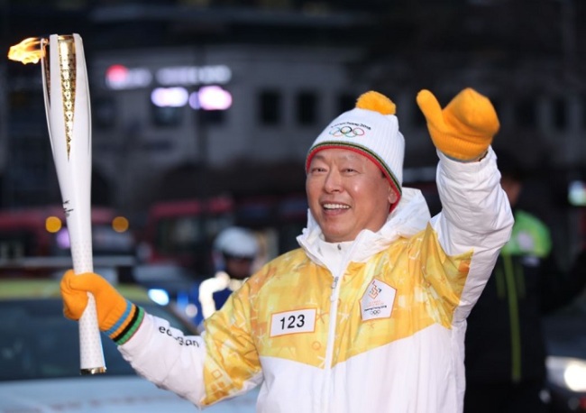 Shin Dong-bin, the head of South Korean retail giant Lotte, carries a torch for the 2018 PyeongChang Winter Olympics in Seoul on Jan. 14, 2018, as part of a nationwide 2,018-kilometer relay. (Yonhap)