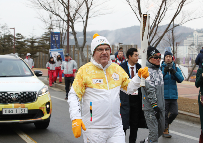 International Olympic Committee President Thomas Bach carries the torch for the 2018 PyeongChang Winter Olympics at Alpensia Resort in PyeongChang, Gangwon Province on Friday. (Yonhap)