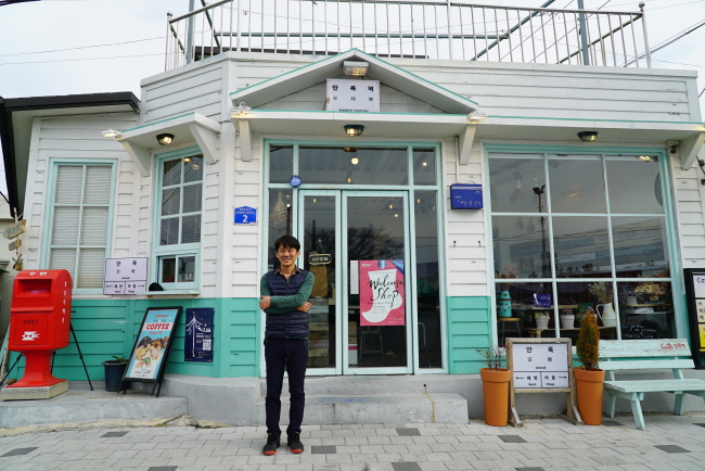 Kim Woo-yeong, who runs a cafe named Anmokyeok, meaning “Anmok Station,” near the Anmok beach, poses for a photo after an interview with The Korea Herald. (Lim Jeong-yeo/The Korea Herald)