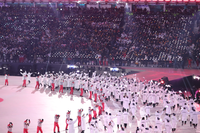 South Korea’s volunteers are seen dancing while South Korean and North Korean athletes march under the Korea Unification Flag symbolizing a unified Korea during the 2018 Winter Olympics Opening Ceremony held in PyeongChang, Gangwon Province, Friday. (Yonhap)