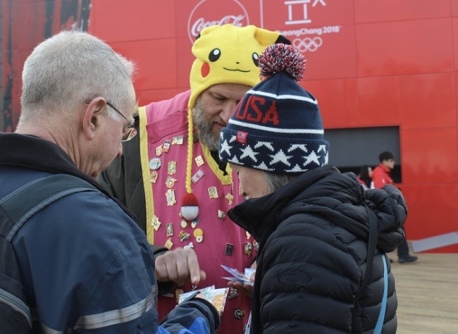 Olympic pin trader Daniel Presburger (center) displays his pins Saturday at the Gangneung Olympic Park, Gangwon Province. Bak Se-hwan/The Korea Herald