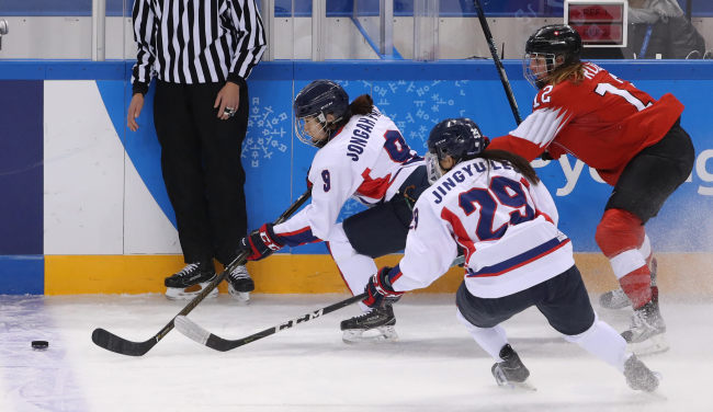 Korean forward Park Jong-ah (L) goes after the puck with Lisa Ruedi of Switzerland (R) chasing her during their classification game in the women's hockey tournament at Kwandong Hockey Centre in Gangneung, Gangwon Province, during the 2018 Winter Olympics on Sunday. (Yonhap)
