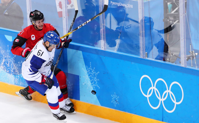 Korean defenseman Lee Don-ku (R) battles Canadian forward Mason Raymond for the puck in the teams' Group A match at Gangneung Hockey Centre in Gangneung, Gangwon Province, during the PyeongChang Winter Olympics on Feb. 18, 2018. (Yonhap)