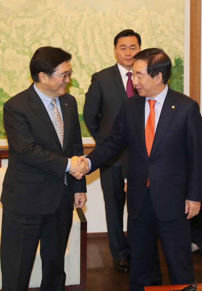 Rep. Woo Won-shik (L), floor leader of the ruling Democratic Party, shakes hands with his main opposition Liberty Korea Party counterpart, Rep. Kim Sung-tae, after agreeing to normalize the parliamentary judiciary committee at the National Assembly in Seoul on Feb. 19, 2018. (Yonhap)