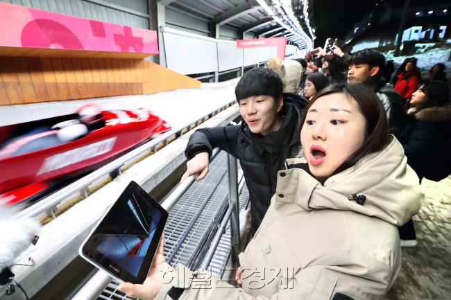 19일 평창 올림픽 슬라이딩 센터에서 관객들이 봅슬레이 경기를 관람하며 ‘싱크뷰’ 서비스에 놀라워하고 있다. [사진=평창공동취재단]