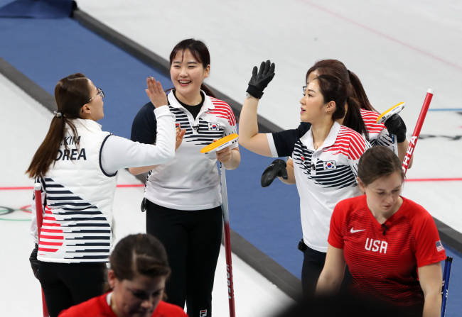 Korea's women's curling team high-fives after winning a round-robin match against the United States at the Gangneung Curling Center during the PyeongChang Winter Olympics on Feb. 20, 2018. (Yonhap)