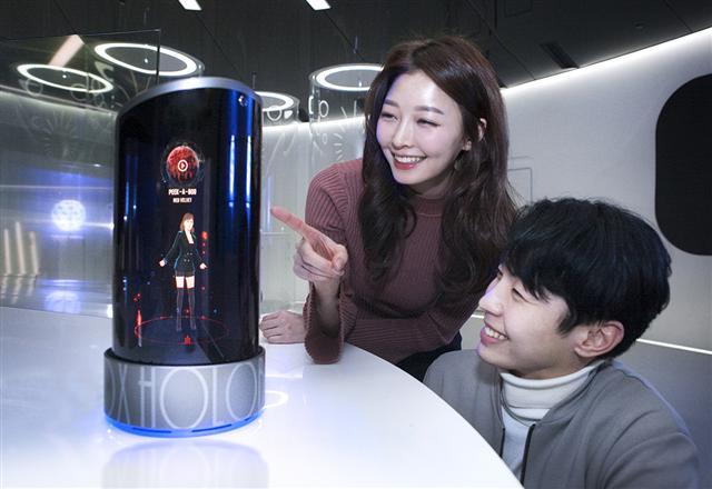 SK텔레콤 모델이 사람 모양의 아바타와 마주보며 이야기 할 수 있는 인공지능 스피커 ’홀로박스‘를 선보이고 있다.  [제공=SK텔레콤]