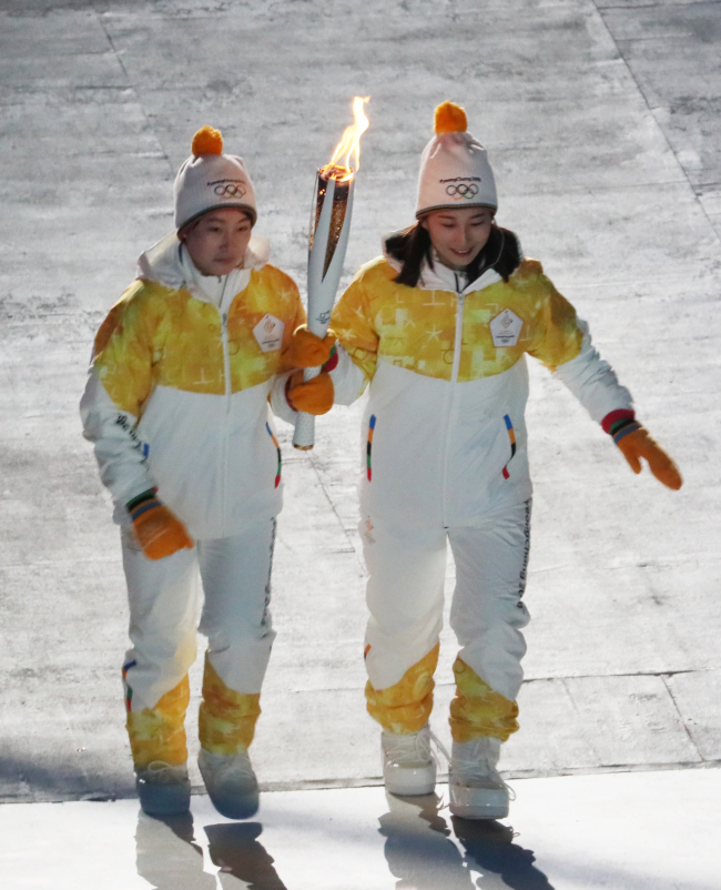 South Korean and North Korean athletes carry the Olympic torch together as the second last runners of the torch relay. The two athletes passed the torch to figure skater Kim Yuna. (Yonhap)