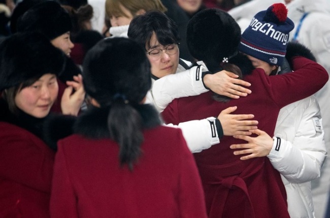 Players of the unified Korean women's hockey team exchange hugs at Gangneung Olympic Village in Gangneung, Gangwon Province, before the North Korean players (in burgundy coats) left South Korea on Feb. 26, 2018, a day after the closing ceremony of the PyeongChang Winter Olympics. (Yonhap)
